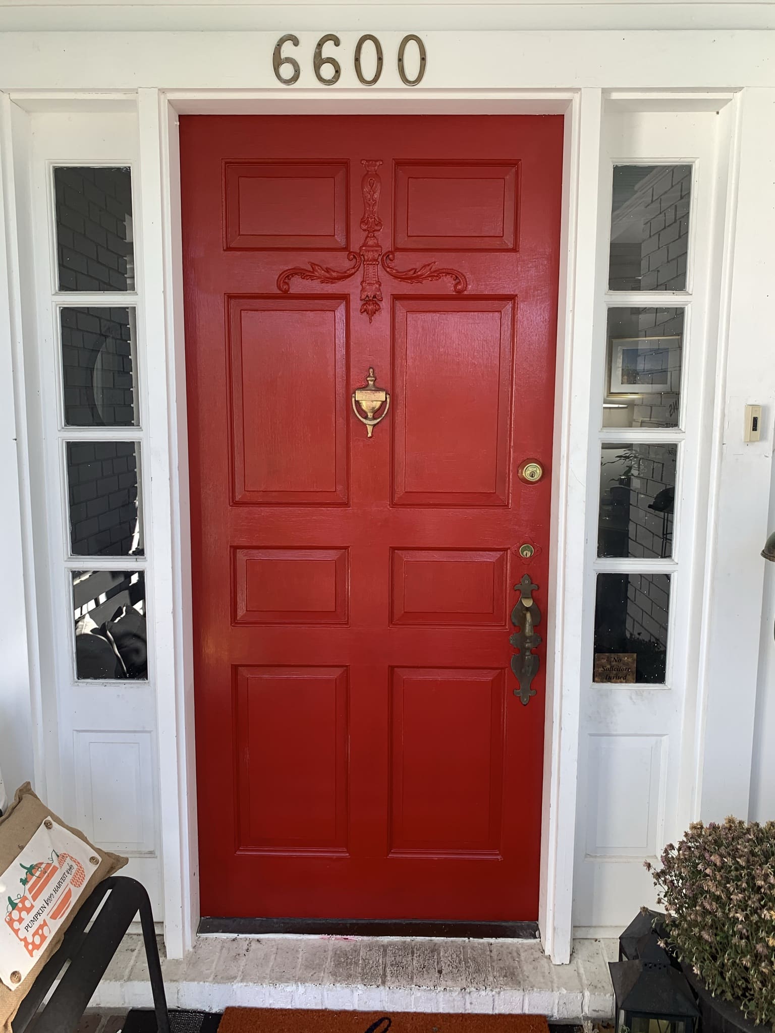Classic red painted front door on a white brick cottage in a recessed porch.