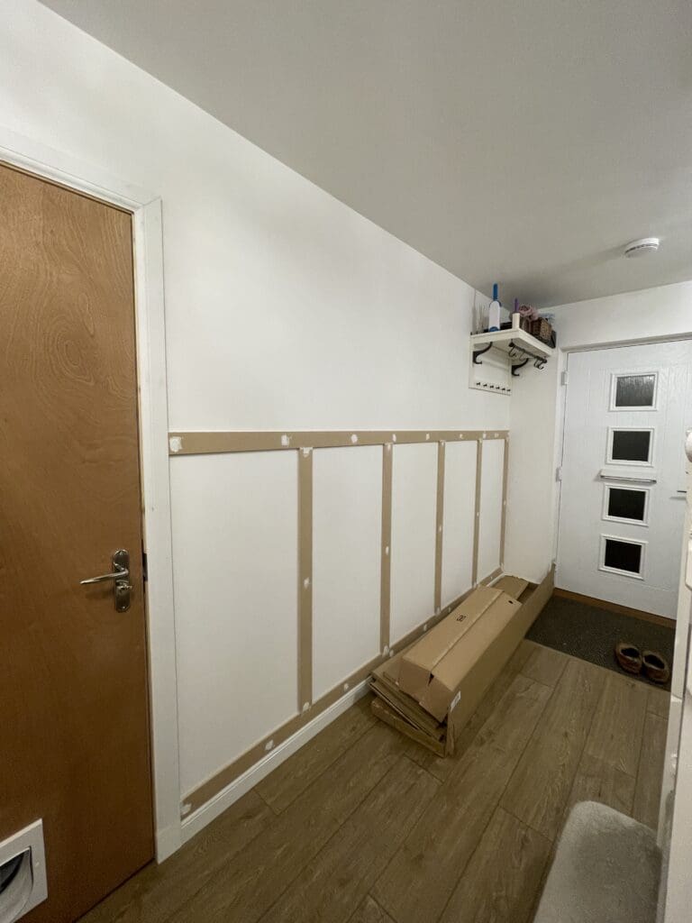 Hallway wall panelling installation in progress showing evenly spaced MDF battens from front door end