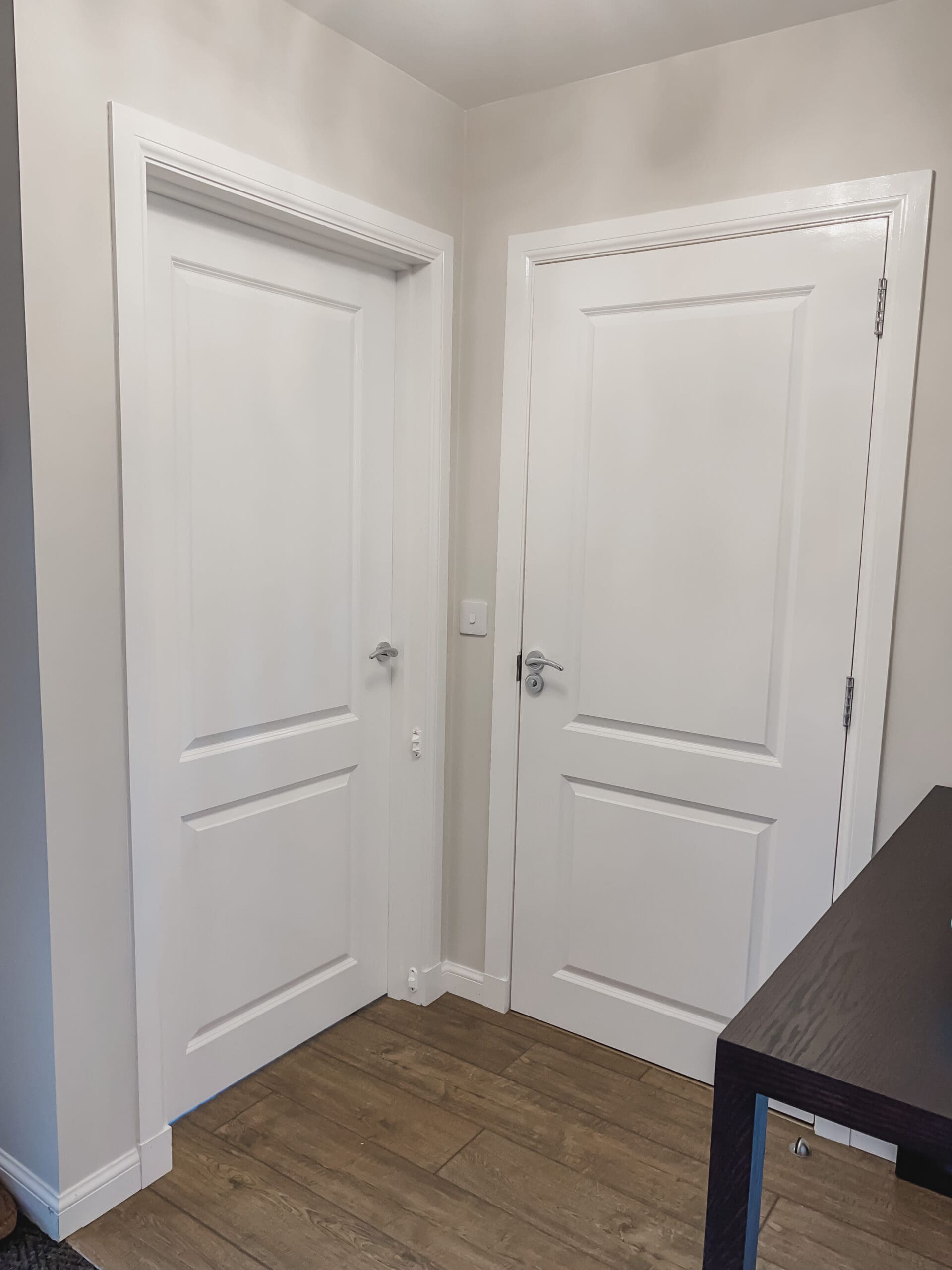 Two white panelled doors in the finished hallway with wooden flooring and Valspar Goose Feathers walls