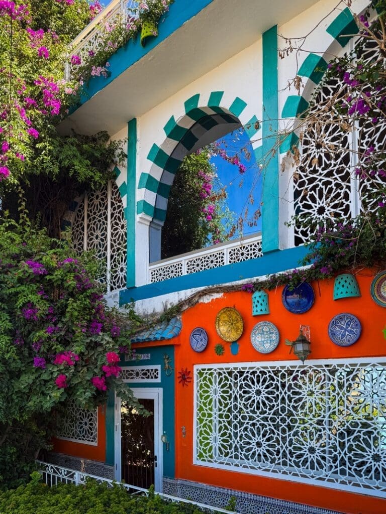Colourful house in Aghroud with a striped arch, decorative plates and flowering bougainvillea