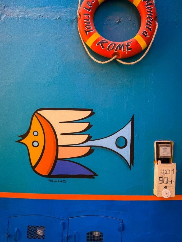 Fish mural and orange lifebuoy on a bright blue wall in Aghroud