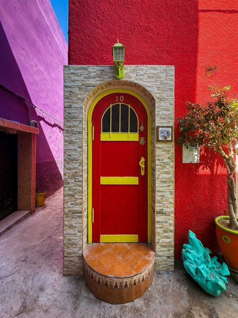 Red and yellow arched doorway between purple and red walls in Aghroud
